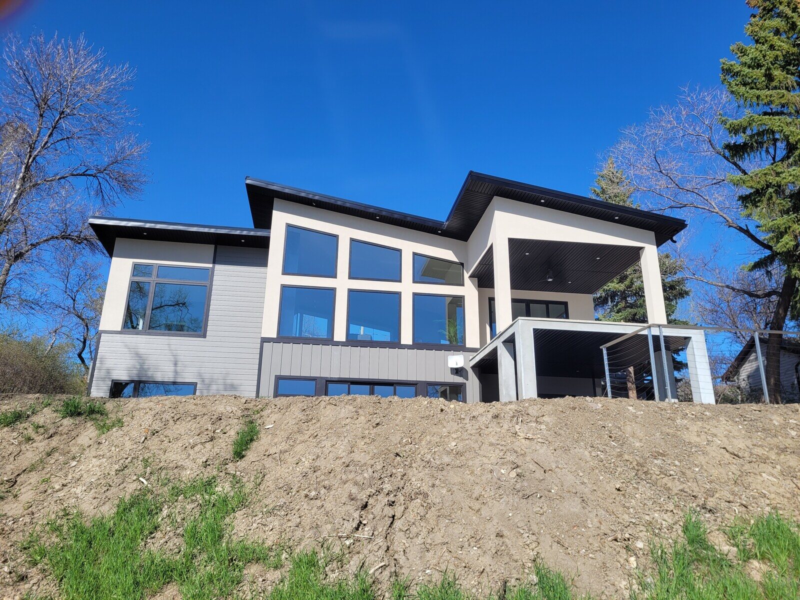 Modern lakeside house with large windows and a covered patio