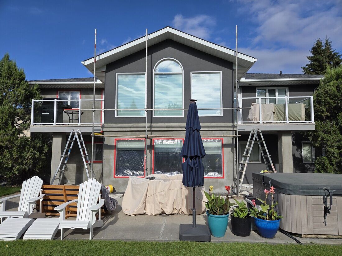 Back of a lakeside house with scaffolding and masking during stucco work