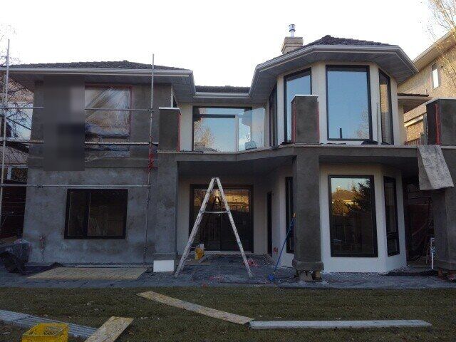 Back of a two-storey house with scaffolding and base coat stucco going on