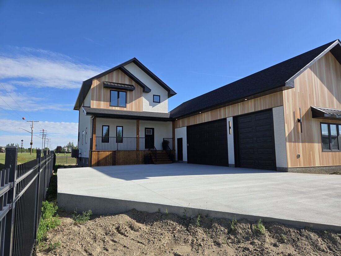 The same house finished with white stucco, cedar siding, a dark roof and black garage doors
