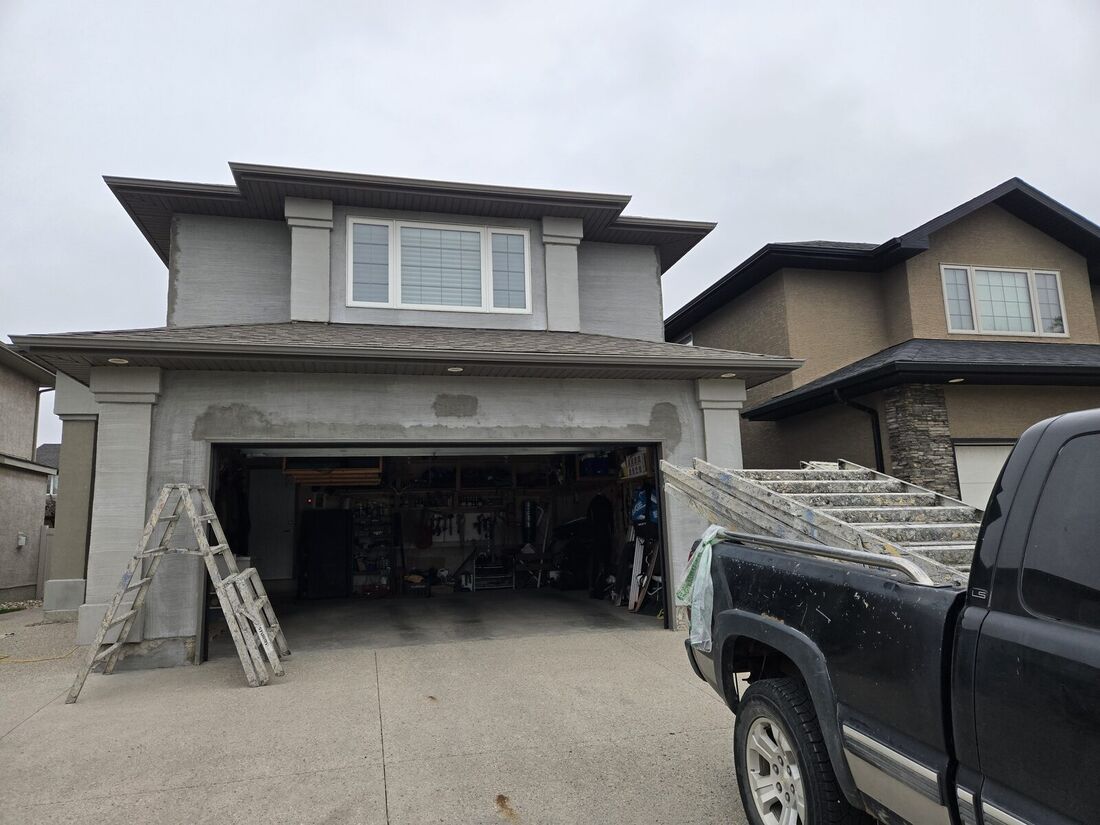 Two-storey house with a grey base coat on the walls and columns, and ladders at an open garage