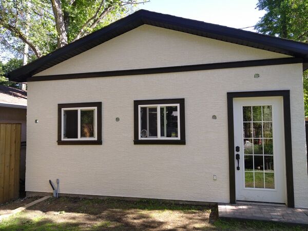 White stucco garage with dark trim and a door