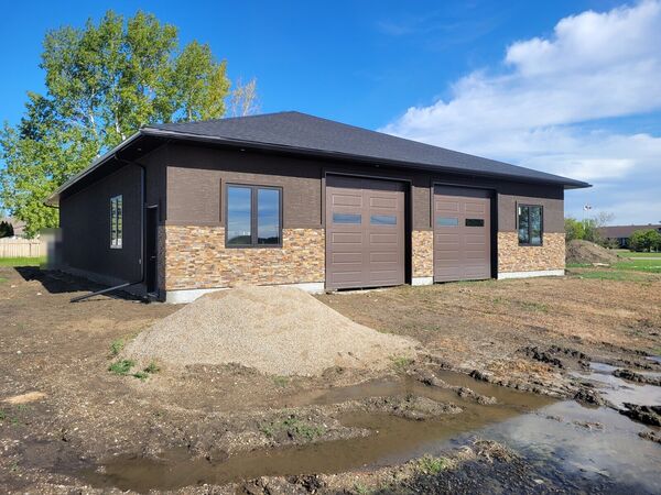 Brown stucco shop with a stone base and two overhead doors in Raymore
