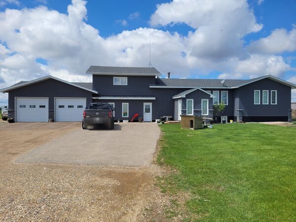 Dark grey stucco house and garage on an acreage near Quinton