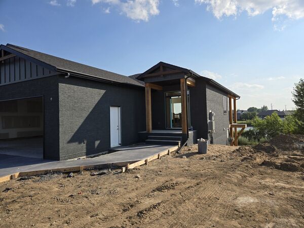 Dark stucco bungalow with timber posts at the entry