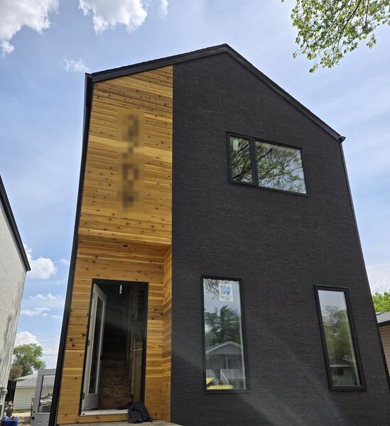 Narrow dark stucco house with a cedar entry strip