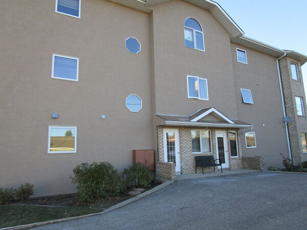Apartment building finished in tan stucco with a brick entry