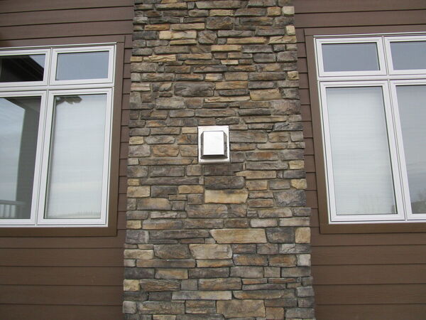 Close-up of a stone chimney column between two windows