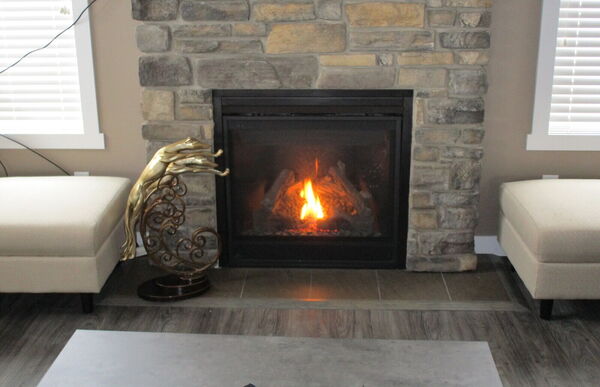 Gas fireplace with a natural stone surround and a wood mantel