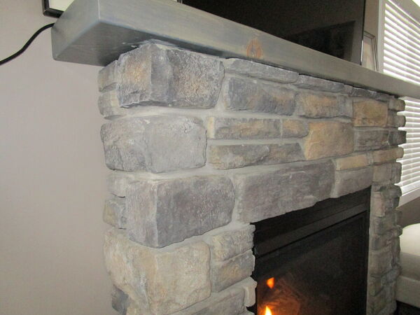 Close-up of stone fireplace corner under a wood mantel