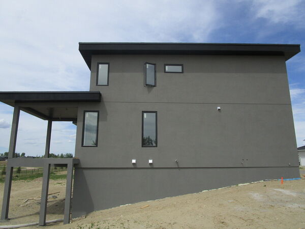 Side of a house finished in smooth grey stucco with a covered deck