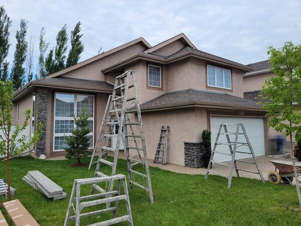 Two-storey house with old pink stucco and ladders