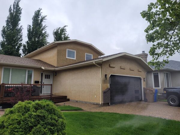 House with tan stucco and a dark garage door