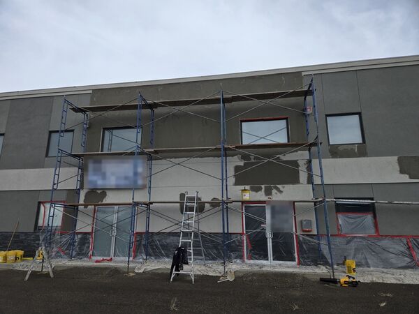 Commercial building with scaffolding and base coat