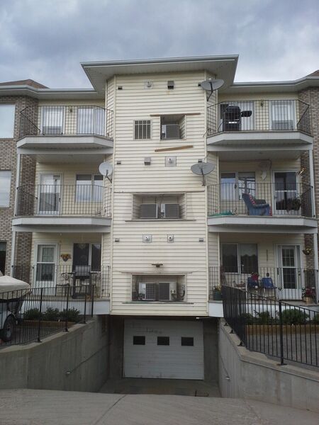 Back of an apartment building with old cream vinyl siding