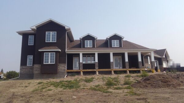 The same house finished in dark siding with stone and white columns